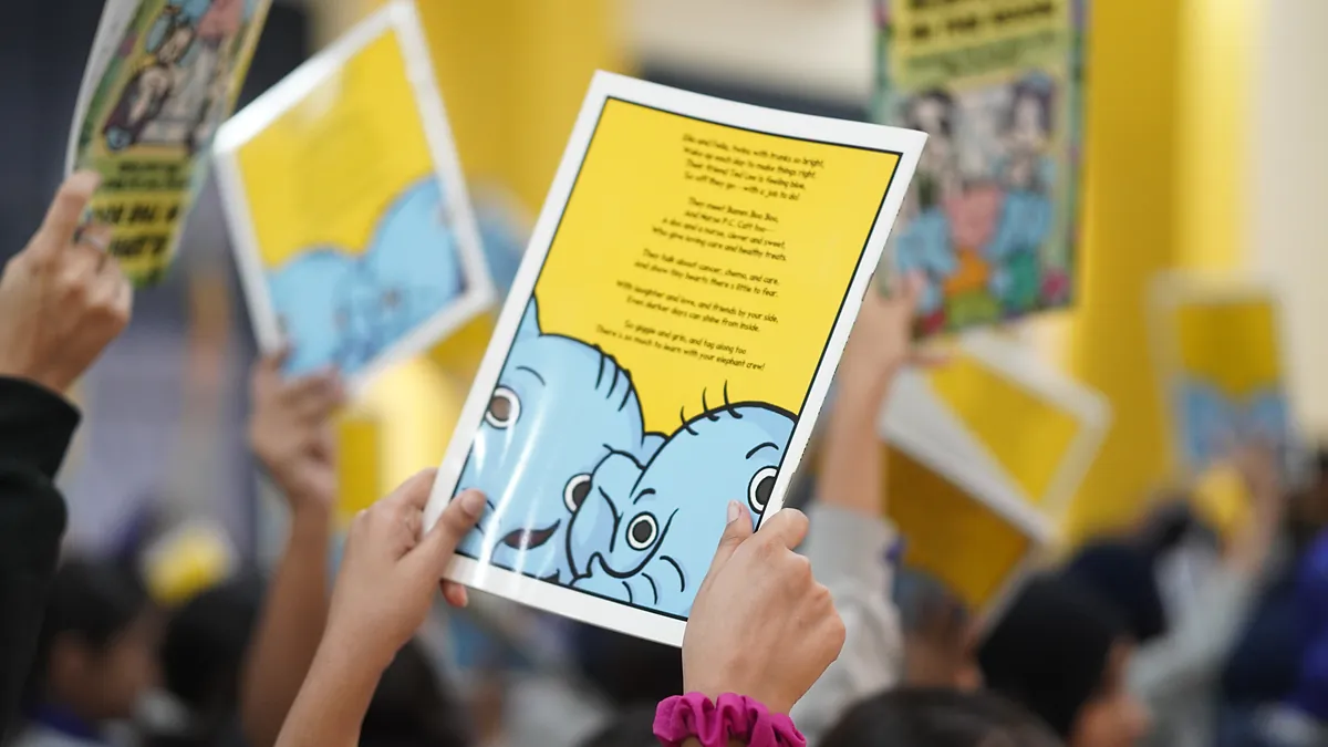 Close-up of a pupil holding up the back cover of Elephants in the Room, showing Ella and Fella the elephant twins.