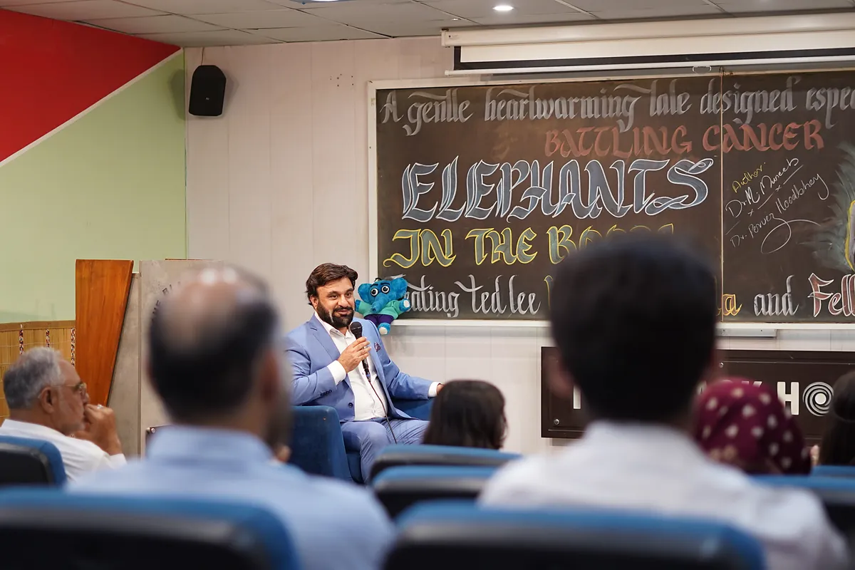The Elephants in the Room launch stage, with the comic's characters drawn across a chalkboard backdrop.