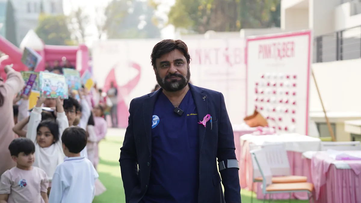Dr Mohammad Muneeb Khan wearing a pink awareness ribbon at a school Pinktober event.