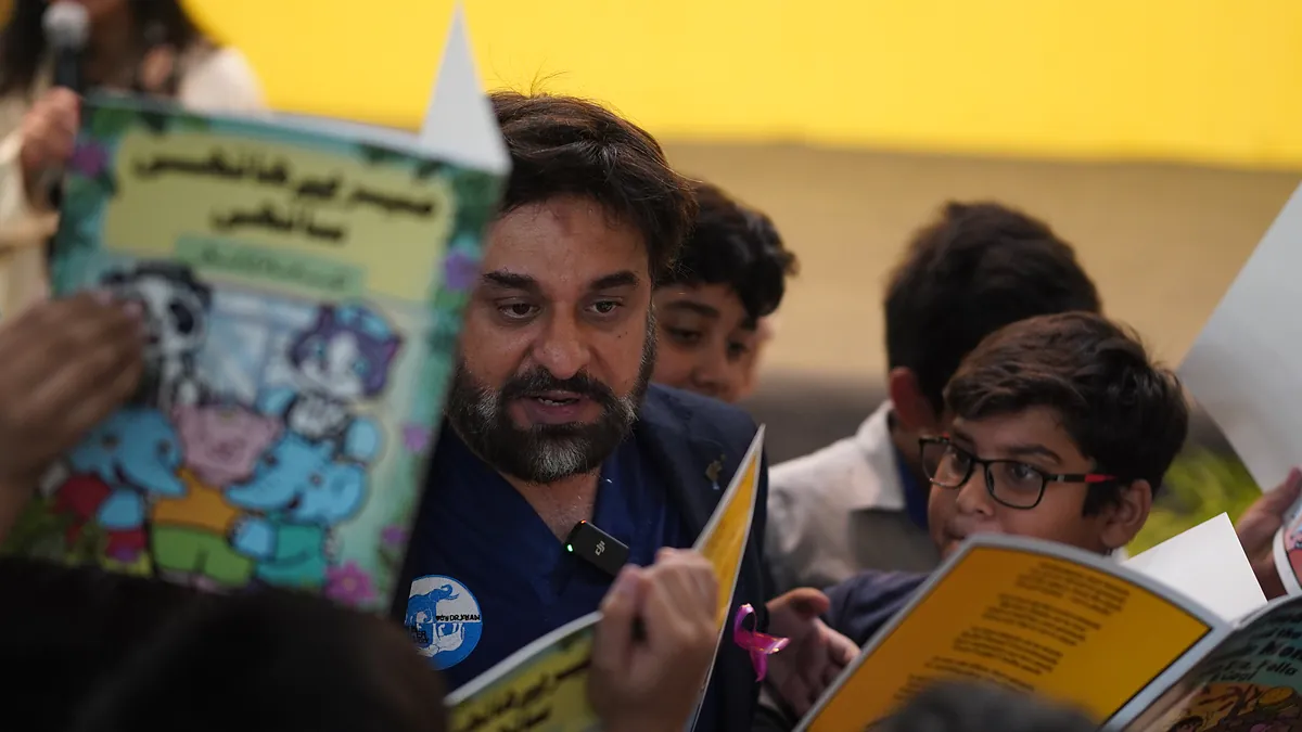Dr Mohammad Muneeb Khan reads the Urdu edition of the prevention comic alongside pupils in the school hall.