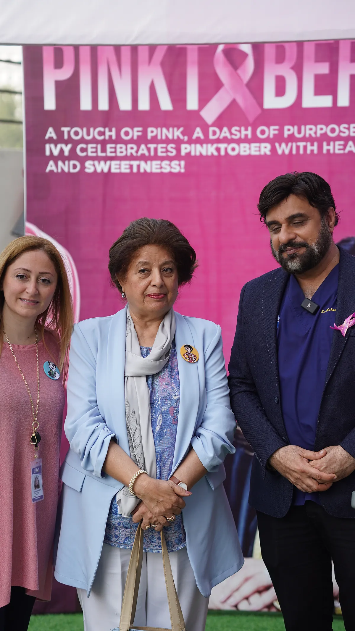 Dr Mohammad Muneeb Khan with guests in front of the school's Pinktober awareness wall.