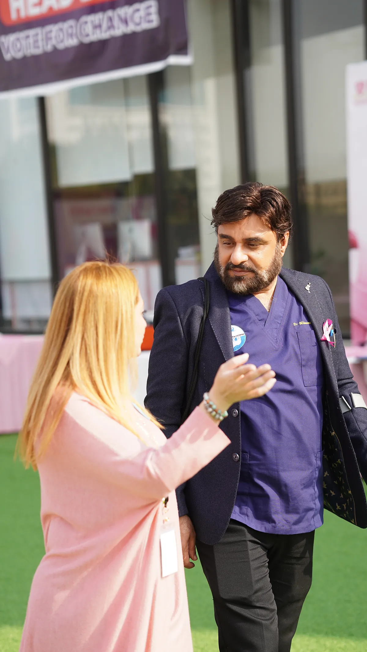 A pink awareness ribbon being pinned on at a school breast-cancer awareness event.
