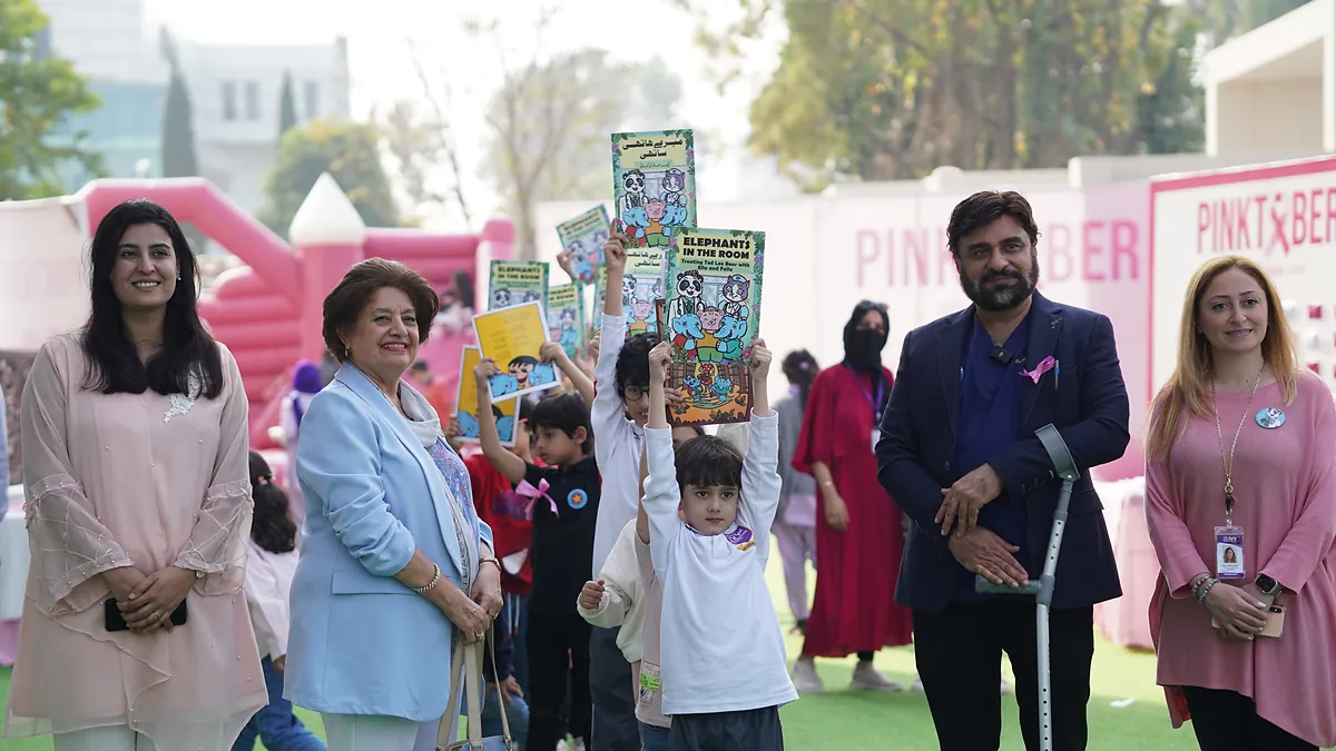 Dr Mohammad Muneeb Khan, staff and pupils with prevention comics at a school Pinktober awareness event.