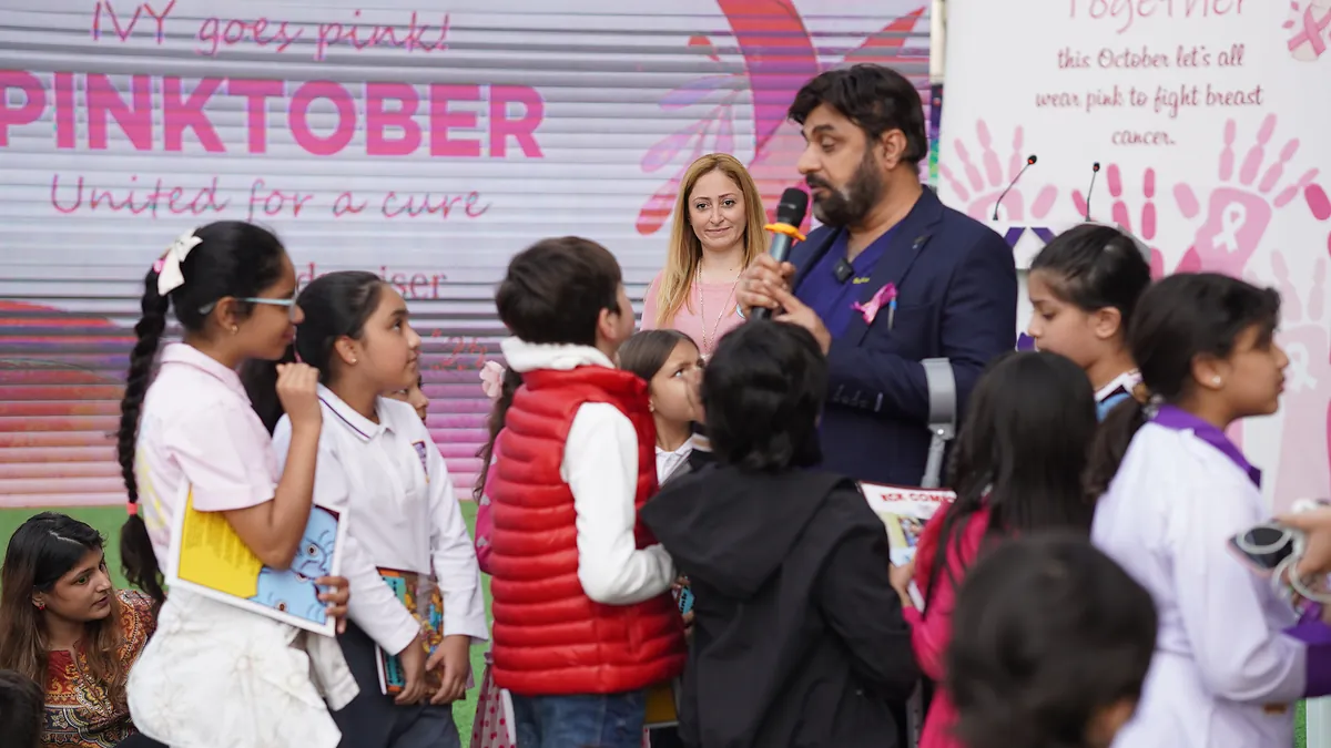 Pupils gather beneath a Pinktober United for a Cure banner at a school breast-cancer awareness day.