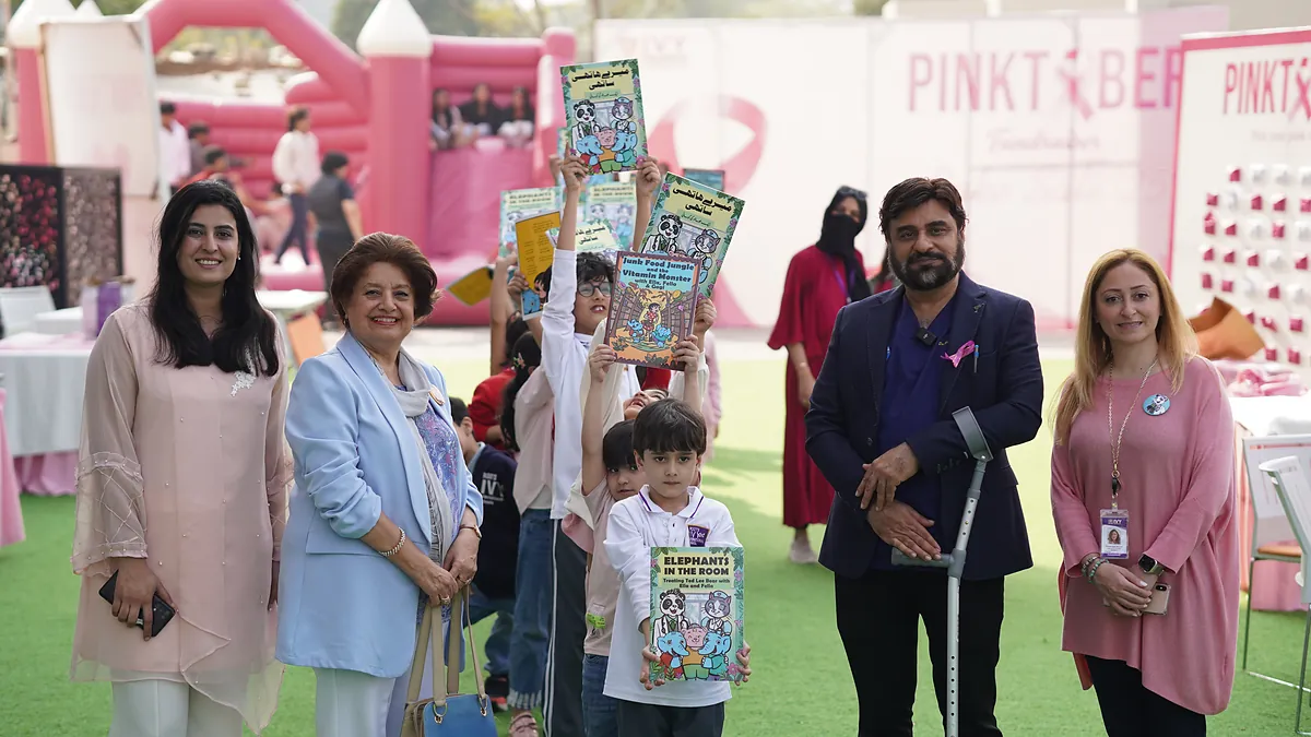 Pupils and organisers hold Killing Cancer Kindly comics together at a school breast-cancer awareness day.