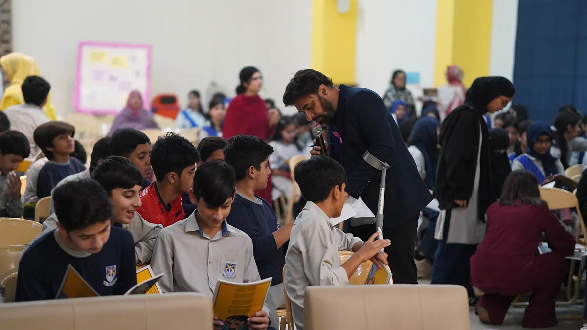 Pupils across a full school hall read and discuss the Killing Cancer Kindly prevention comics.