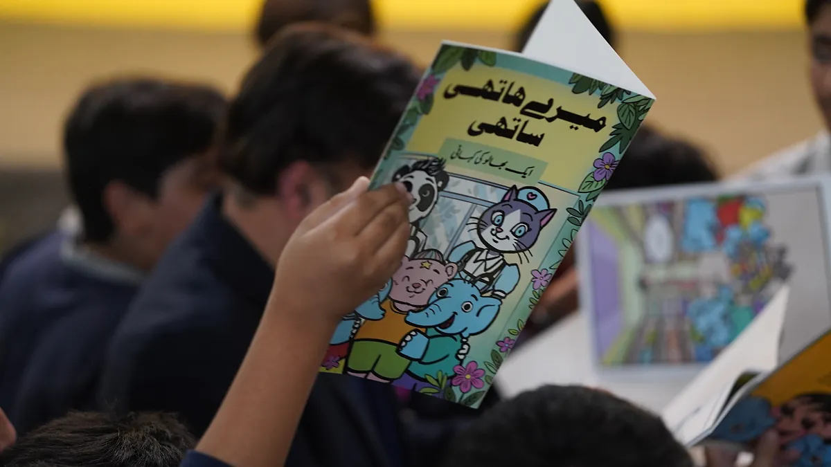 A pupil reads the Urdu edition of the Killing Cancer Kindly elephant comic during the school assembly.