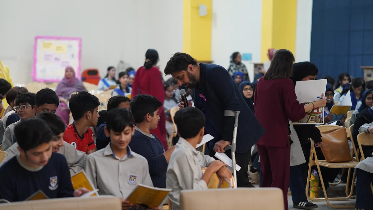 A wide view of the school hall as pupils sit reading their Killing Cancer Kindly comics.