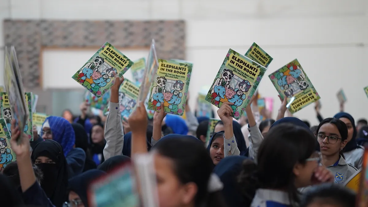 Schoolchildren hold copies of the comic Elephants in the Room above their heads at a whole-school prevention assembly.