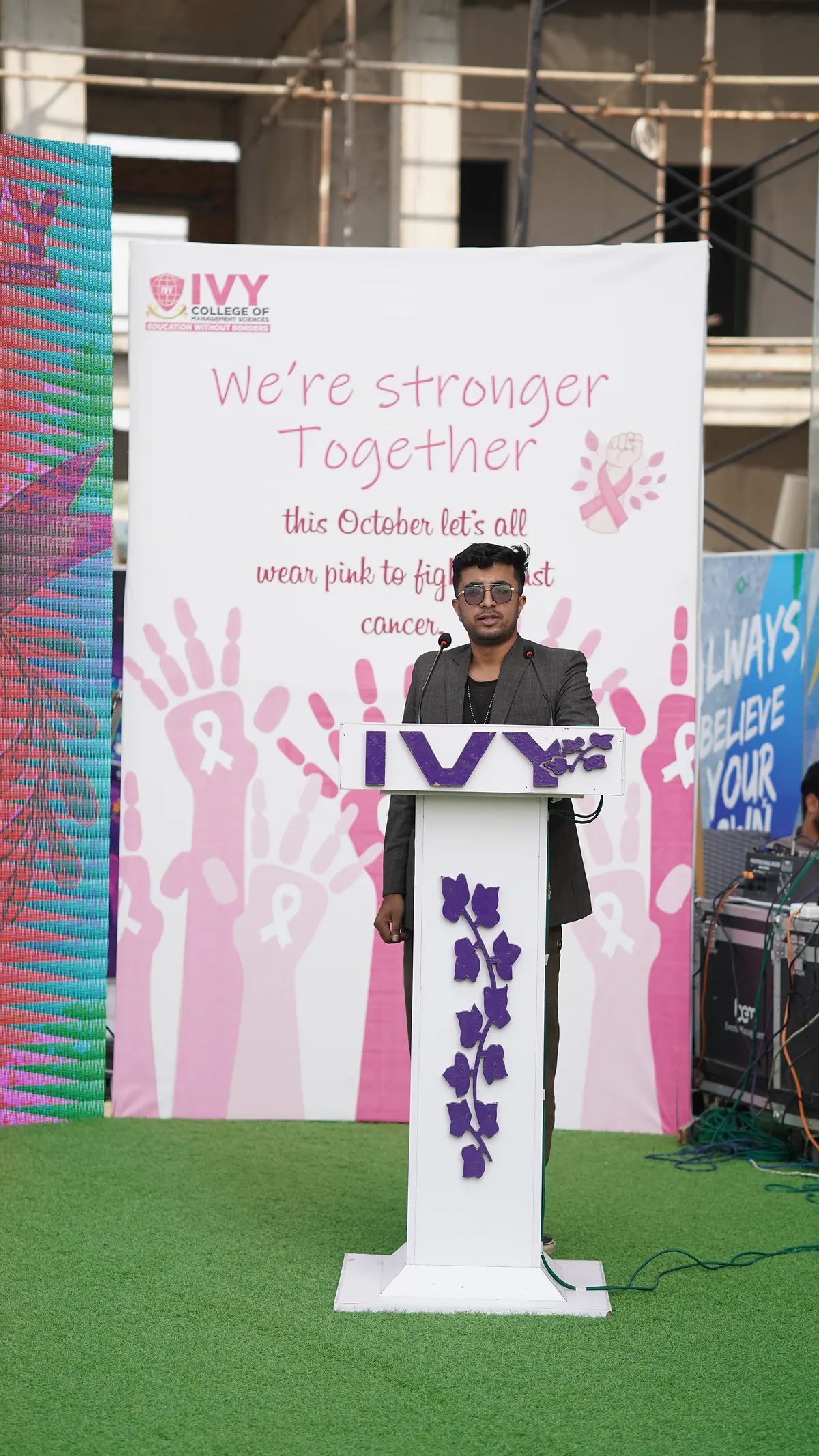 A school lectern dressed for Pinktober with a We're Stronger Together breast-cancer awareness banner.